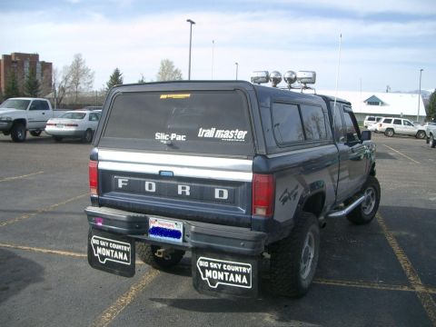 1992 Ford Ranger - This Ford pickup truck is equipped with a camper shell and mud flaps, seen from the rear in a parking lot.