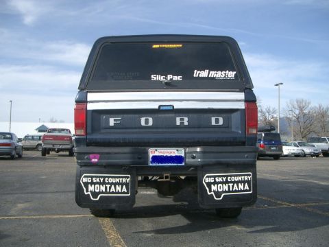 1992 Ford Ranger - Rear view of a Ford truck with a camper shell and Montana-themed mud flaps in a parking lot.