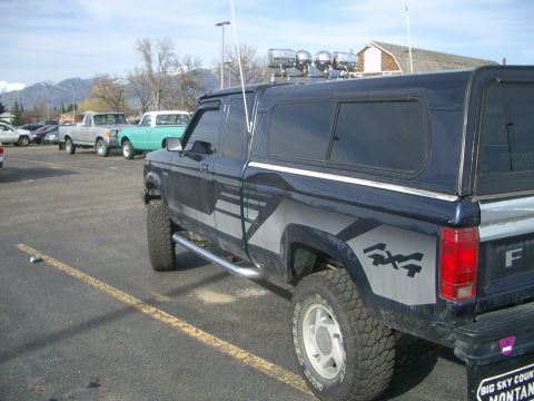 1992 Ford Ranger - Side view of a 1992 Ford Ranger pickup truck with a camper shell and 4x4 graphics.