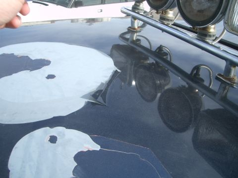 1992 Ford Ranger - Peeling paint on the hood of a dark vehicle, with roof-mounted lights and another vehicle in the background.