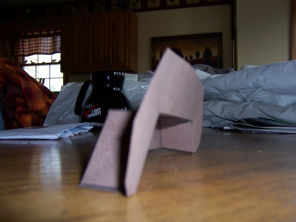 Cardboard cutout on a table with a coffee mug and papers