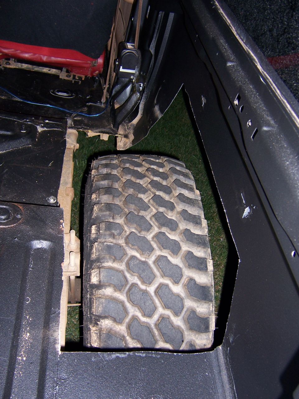 Spare tire mounted inside vehicle cargo area, next to seatbelt