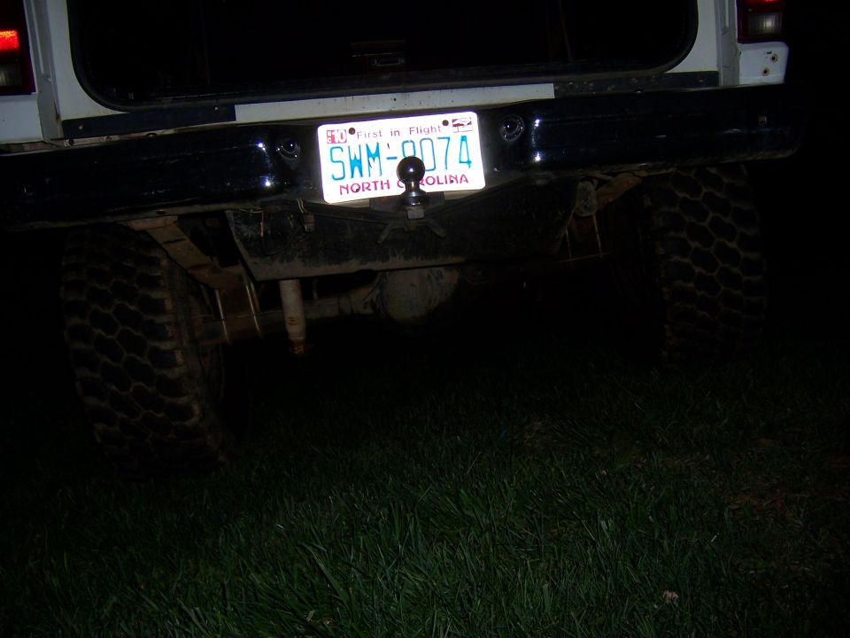 Rear of white SUV with trailer hitch and license plate SWM-9074