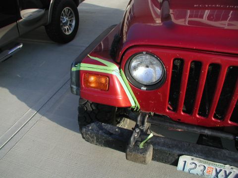 1998 Jeep TJ - Front view of a red 1998 Jeep TJ, showing green tape applied to the fender and headlight area.