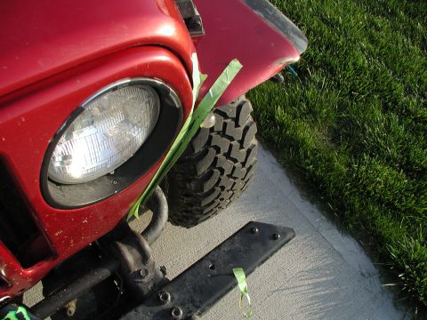 1998 Jeep TJ - Close-up of a red Jeep TJ's front fender, headlight, and tire with green tape applied.