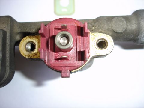 1993 Mazda MX-3 - A close-up view of a single automotive part, a fuel rail component with a red connector.