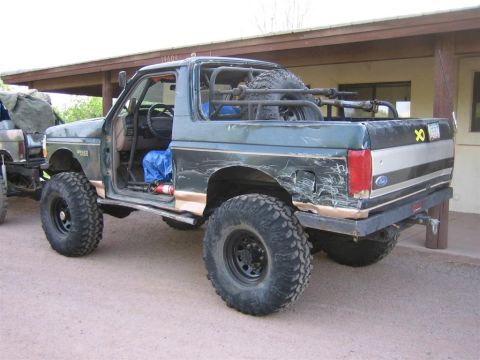 1994 Ford Bronco - This heavily modified 1994 Ford Bronco features oversized off-road tires, a custom roll cage, and a spare tire rack in the bed.