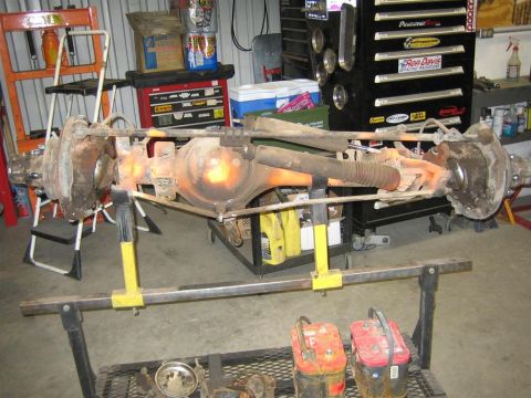 1987 Suzuki Samurai - A vehicle's front axle assembly is shown disassembled and supported on a stand in a workshop environment.
