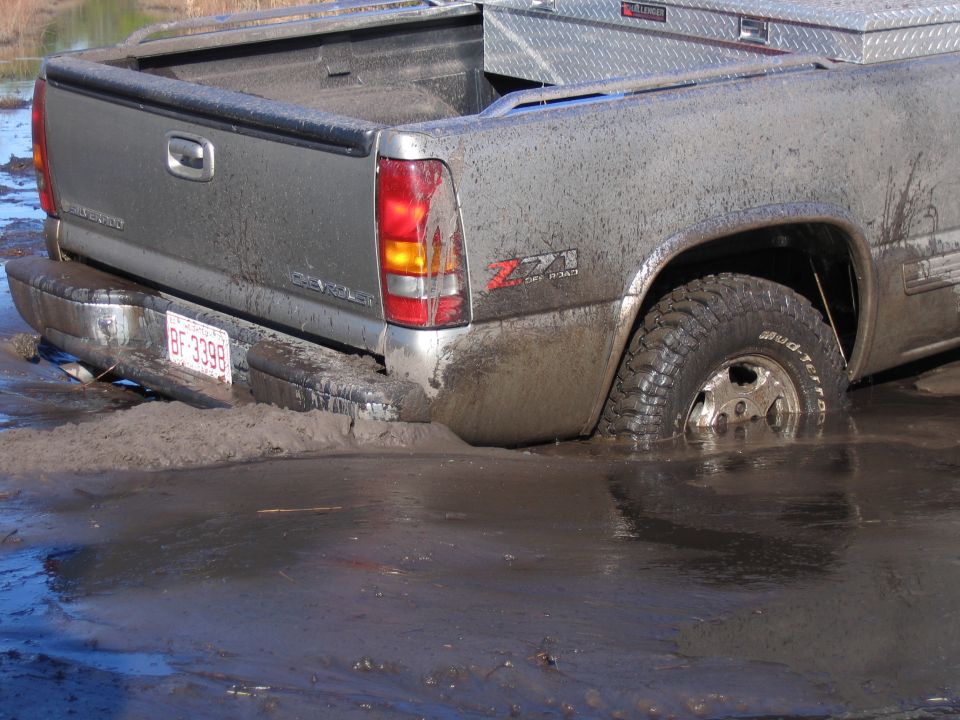 Gray Chevrolet Z71 pickup buried to the axles in mud, red plate reading BF 3398