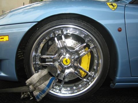 1990 Ford Bronco - Close-up of a polished chrome five-spoke Ferrari wheel with a yellow caliper, drilled brake rotor, and the prancing-horse hub badge.