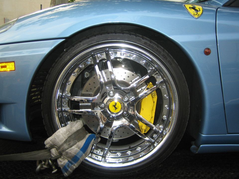 Close-up of a chrome Ferrari wheel with yellow brake caliper and drilled rotor