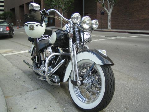 1990 Ford Bronco - Front three-quarter view of a black cruiser motorcycle with a windshield, triple headlights, whitewall tire, and chrome forks at a curb.