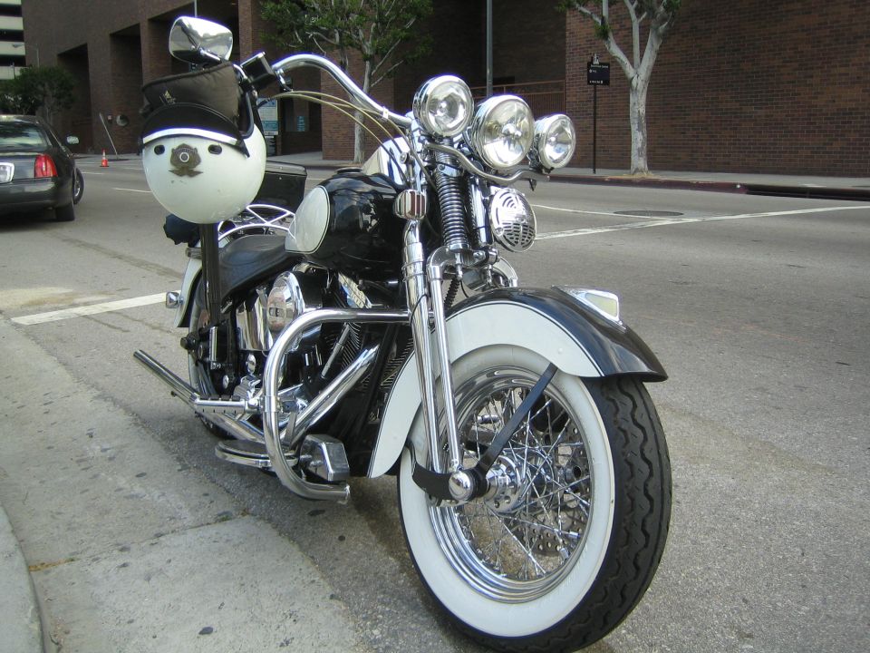 Front view of a black cruiser motorcycle with windshield and triple headlights on a street