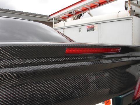 1993 Ford Taurus - The rear of a car features a carbon fiber trunk lid and a red brake light bar, with a 2006 license plate visible.