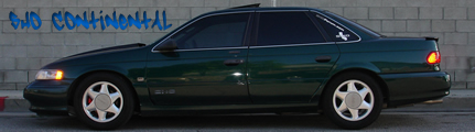 1993 Ford Taurus - Side profile of a dark green 1993 Ford Taurus sedan with tinted windows.