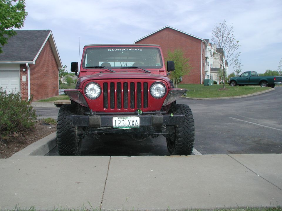 Red Jeep Wrangler parked on sidewalk, KCJeepClub.org sticker on windshield, license plate 123 XXA