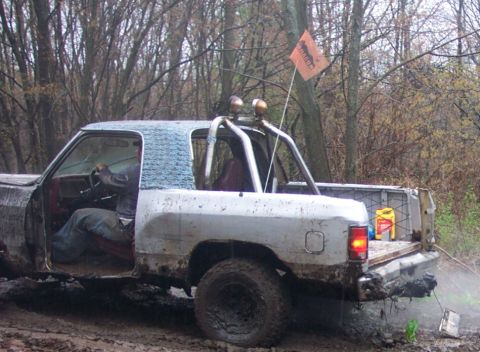 1978 Ford Bronco - This pickup truck is stuck in the mud with a flag on top and fluids in the bed.