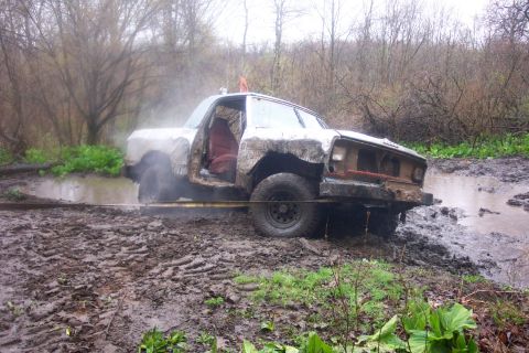 1978 Ford Bronco - This heavily modified off-road vehicle appears to be stuck in a muddy area, with one door open and being pulled by a rope.