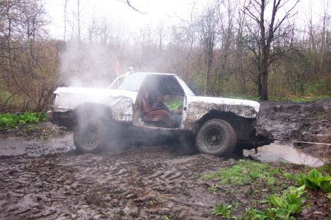 1978 Ford Bronco - A white off-road vehicle is stuck in the mud, emitting steam as it struggles to move.
