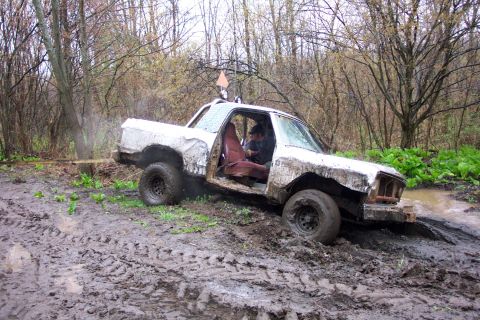 1978 Ford Bronco - This heavily modified off-road vehicle is deeply stuck in the mud, surrounded by a wet, wooded environment.