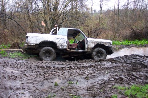 1978 Ford Bronco - Off-road vehicle struggling through a muddy terrain with water visible.