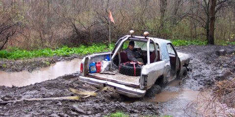 1978 Ford Bronco - This off-road truck is deeply stuck in a muddy trail, with a spare tire and fuel cans visible in the bed.