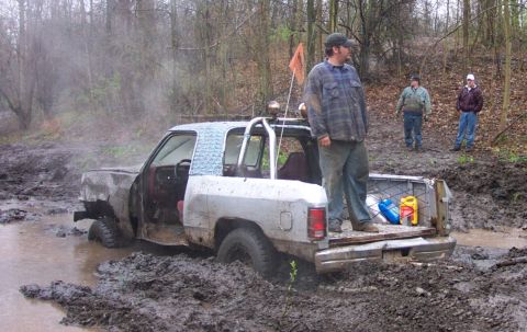 1978 Ford Bronco - Pickup truck stuck in mud, with people observing the situation.