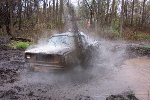 1978 Ford Bronco - A 1978 Ford Bronco navigates a muddy trail, sending water and mud flying.