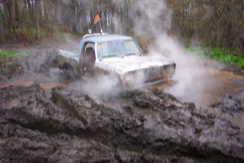 1978 Ford Bronco - Pickup truck struggling through thick mud, steam billowing around it.