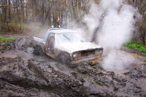 1978 Ford Bronco - This pickup truck is deeply stuck in a muddy trail, with a large splash erupting from the front.