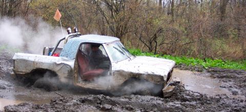 1978 Ford Bronco - A white pickup truck is stuck deep in mud with steam rising around it.