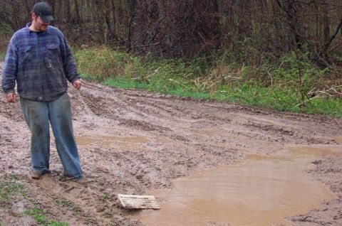 1978 Ford Bronco - A man pulls a keyboard through a muddy, rutted road, suggesting an unusual situation.