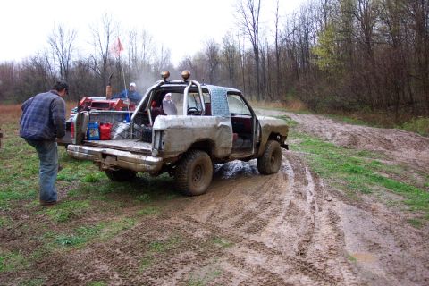 1978 Ford Bronco - A heavily modified off-road vehicle navigates a muddy track in a wooded area.