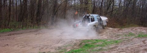 1978 Ford Bronco - Truck driving through mud and dust on a wooded trail.