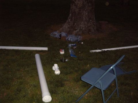 1988 Ford Bronco - Debris and construction materials are spread across a grassy area at night, with a folding chair in the foreground.