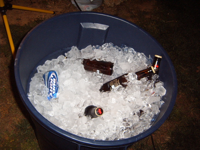 Blue trash can filled with ice and beer bottles and a Bud Light can