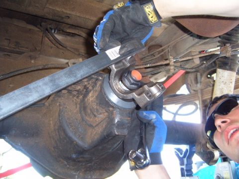 1988 Ford Bronco - Close-up of a mechanic performing maintenance on a vehicle's rear differential assembly.