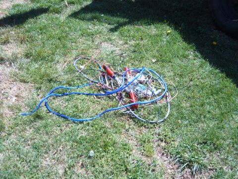 1988 Ford Bronco - A messy bundle of electrical wires and cables lies on a grassy surface, red and blue insulation.