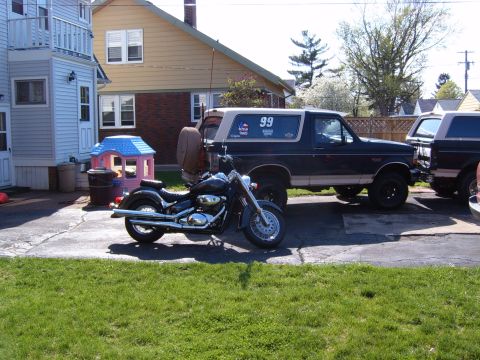 1993 Ford Bronco - A dark blue 1993 Ford Bronco is parked next to a motorcycle, with another Bronco visible to the right.