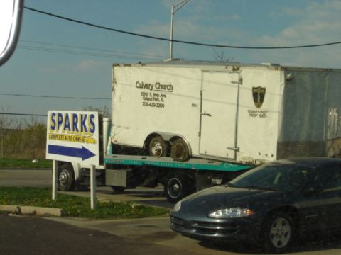 1992 Ford Bronco - A trailer is being transported on a flatbed truck, with a dark sedan visible in front.