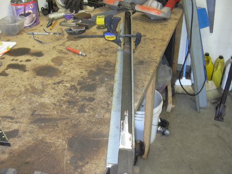 1991 Ford Bronco - A metal component is secured with clamps on a cluttered workbench, suggesting a repair or fabrication process.