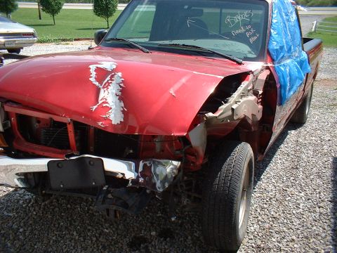 1999 Ford Ranger - This heavily damaged red Ford Ranger shows extensive front-end collision impact.