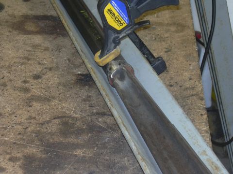 1991 Ford Bronco - A Quick-Grip clamp is used to hold a metal pipe in place on a workbench.