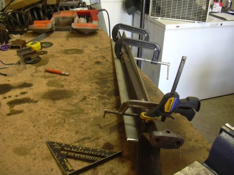 1991 Ford Bronco - A cluttered workbench displays tools and metal components, suggesting ongoing fabrication or repair work.