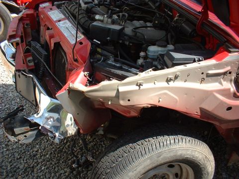 1999 Ford Ranger - The front of a 1999 Ford Ranger shows significant damage, with the engine compartment exposed.