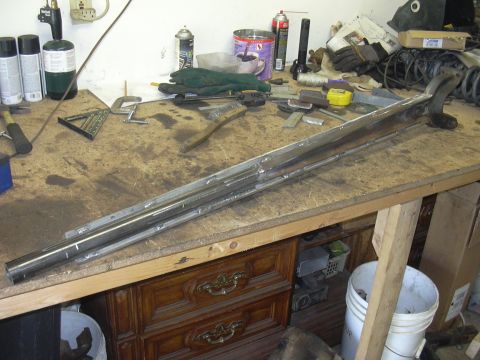 1991 Ford Bronco - A metal suspension part rests on a workbench with tools and supplies.