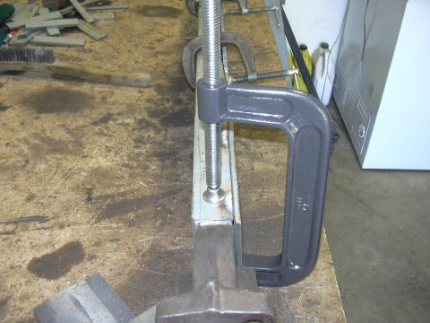 1991 Ford Bronco - A C-clamp secures a metal component on a cluttered workbench, with various tools and materials visible in the background.