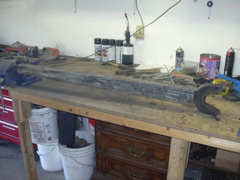 1991 Ford Bronco - A metal beam is secured in a vise on a workbench, surrounded by various tools and supplies.