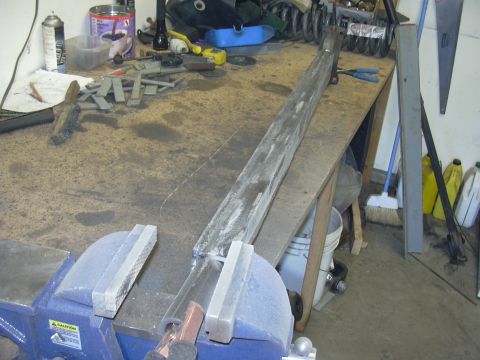 1991 Ford Bronco - A metal bar is secured in a vise on a workbench, surrounded by various tools and metal pieces.