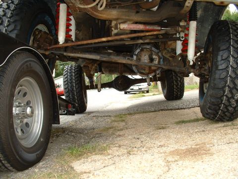 1978 Ford Bronco - The underside of a lifted 4x4 vehicle reveals its heavy-duty suspension and large off-road tires.